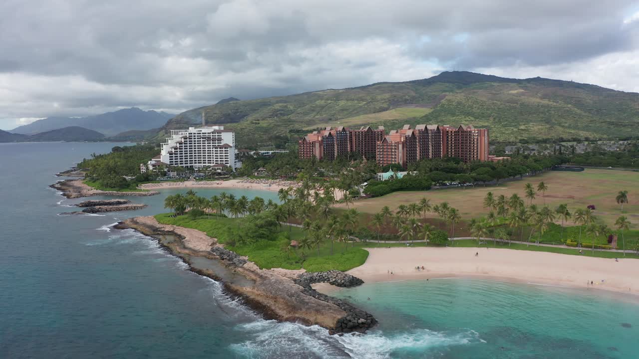 Ripresa aerea in dolly lungo lagune costiere con resort di lusso sullo sfondo sull'isola di O'ahu, Hawaii.