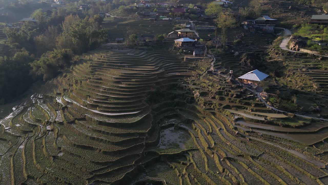 tomada aérea de un avión no tripulado volando sobre terrazas de arroz verde brillante y aldeas de las tierras altas en las montañas de sapa, vietnam