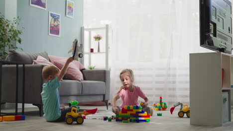 toddler plays with airplane while preschooler builds wall