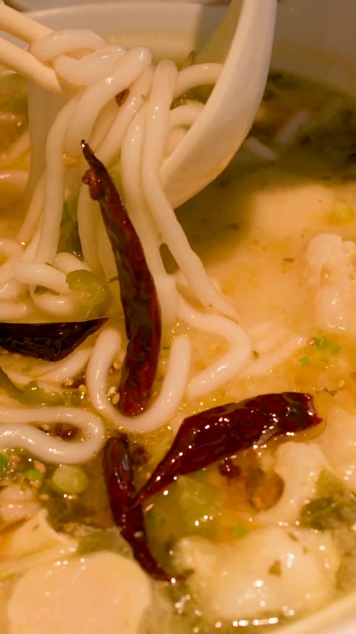 Primo piano mentre si mangia zuppa di noodle piccante con bacchette e cucchiaio