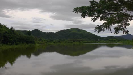 4K-B-Roll-Aufnahmen-Eines-Sees,-Umgeben-Von-Bergen-Und-Grünen-Waldbäumen-In-Thailand