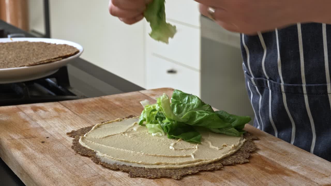 Chef tucks lettuce inside flaxseed wrap with hummus spread