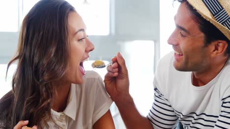 man feeding food to woman