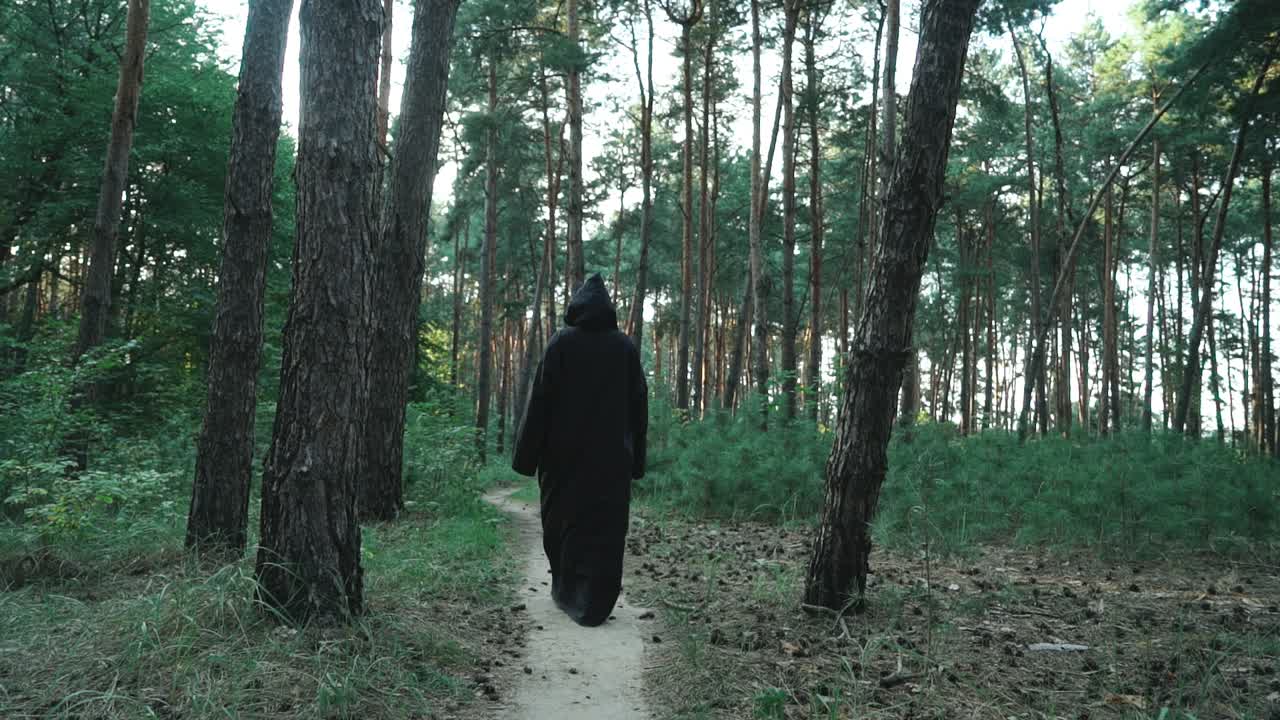 Evil ghost hooded creature walking across forest. Halloween