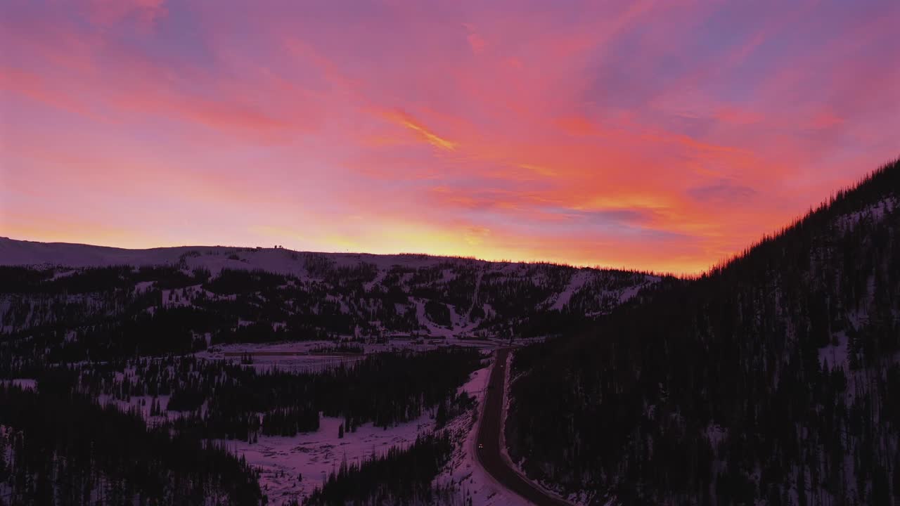 Vista aerea del profondo crepuscolo che cala sulle San Juan Mountains. Il cielo mostra uno splendido gradiente magenta sopra la tortuosa Highway 160, creando un'atmosfera invernale cupa e intensa.