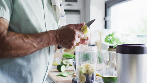 un hombre bi-racial feliz preparando una bebida saludable en la cocina.