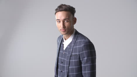 young man in suit runs hand through hair, turns, waist up