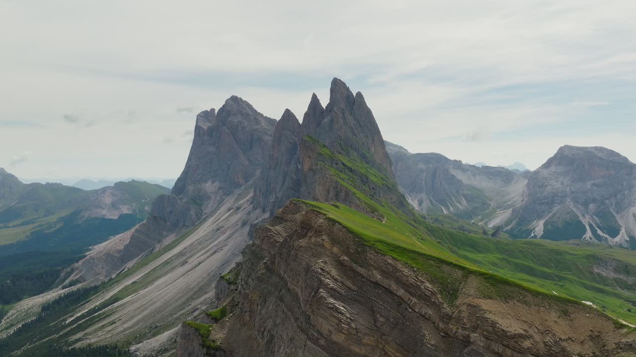Drone glides along ridgeline at Seceda with rocky peaks and layered landscape below