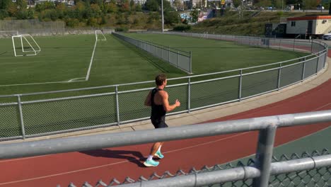 male athlete running on athletic track - tracking shot