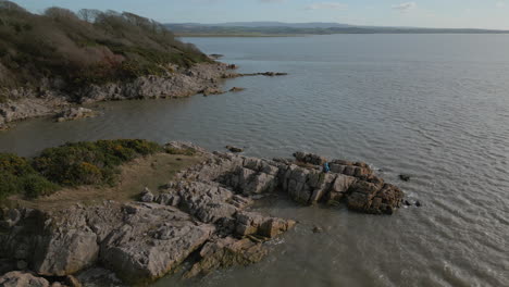 Lone-hiker-on-rocky-outcrop-staring-at-the-horizon-with-ocean-reveal-at-Jenny-Brown's-Point-Silverdale-UK