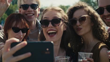 group of caucasian friends making funny faces for a common selfie on music festival.