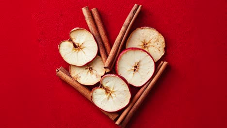 rebanadas de manzana seca y palillos de canela sobre un fondo rojo