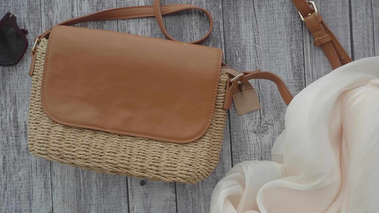 Flat lay of handbag, sunglasses, and scarf on wooden background