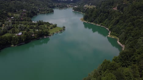 aerial panning up shot of the beautiful landscape of forests and lakes in a natural ecosystem - paltinu of doftana valley in romania