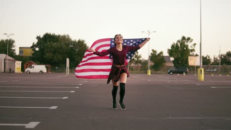 jovem garota americana feliz correndo enquanto segurava a bandeira americana e olhando para a câmera