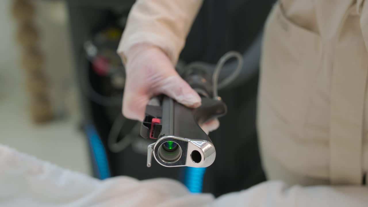 Professionele hand in handschoen die een laserapparaat met groene straal vasthoudt