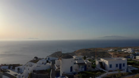 Aerial-pull-back-shot-of-Oia-in-Santorini,-Greece-during-golden-hour