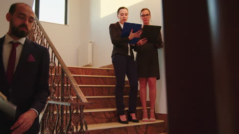 woman colleagues talking standing on stairs