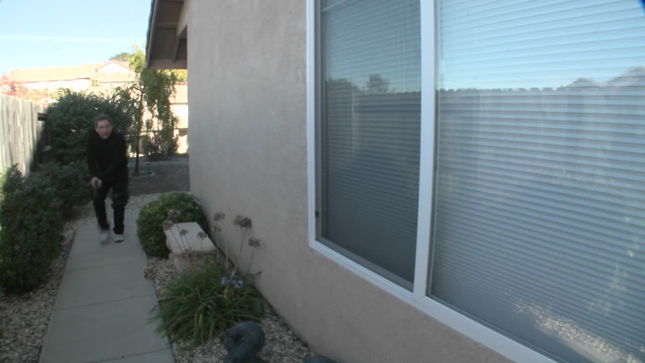 스와트 또는 데아 팀의 장교가 마약 단속 중에 동료 장교를 보호하기 위해 집 옆으로 이동합니다.