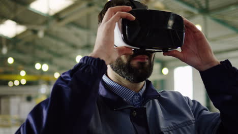 close-up view of caucasian man putting on vr glasses in a big factory