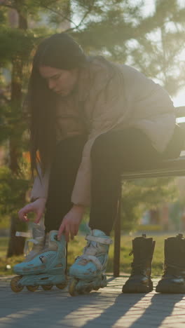 una persona sentada en un banco en un parque, soltando las correas de una patineta mientras usa otra. la escena captura un momento tranquilo de transición de patinaje a calzado regular