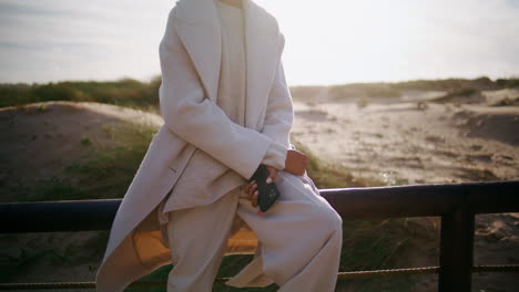 businesswoman body lean railings in sunlight. unknown stylish woman hold phone