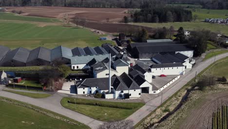 Aerial-view-of-Fettercairn-whisky-distillery-on-a-sunny-spring-day,-Aberdeenshire,-Scotland