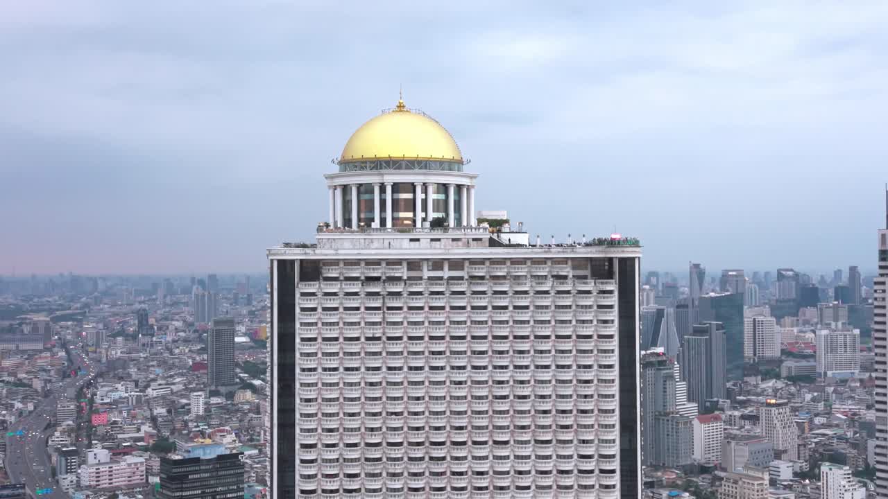 Vista aérea da State Tower elevando-se sobre o horizonte de Banguecoque, com sua cúpula dourada e design neoclássico destacando-se sobre o distrito do rio Chao Phraya. (2)