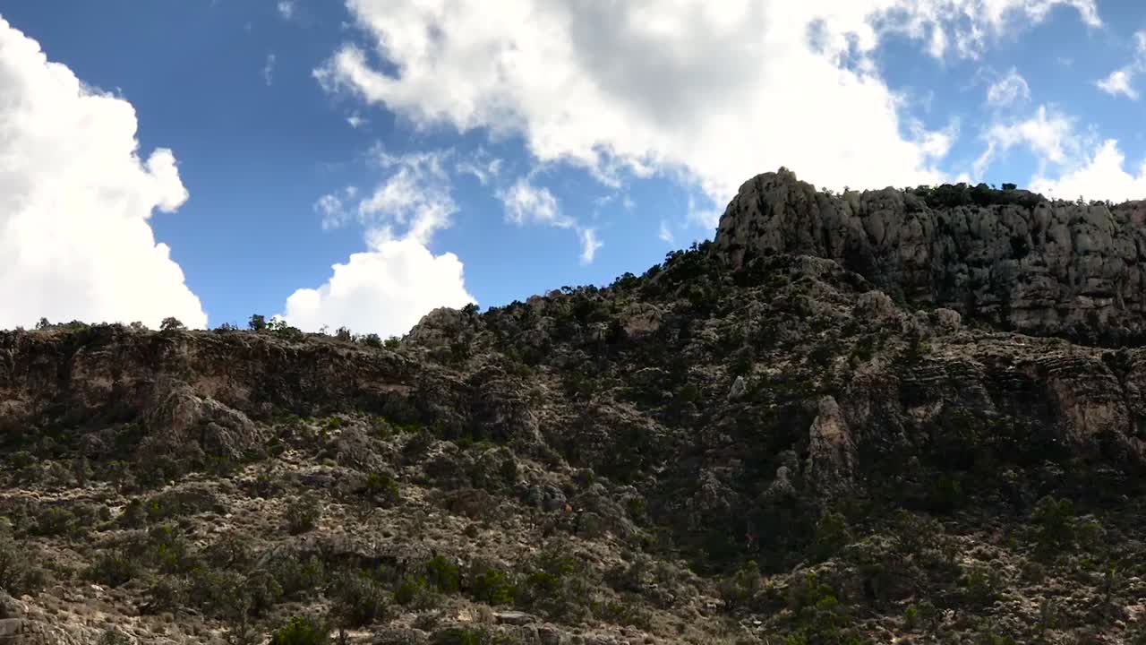 Clouds rolling over mountain top in desert.