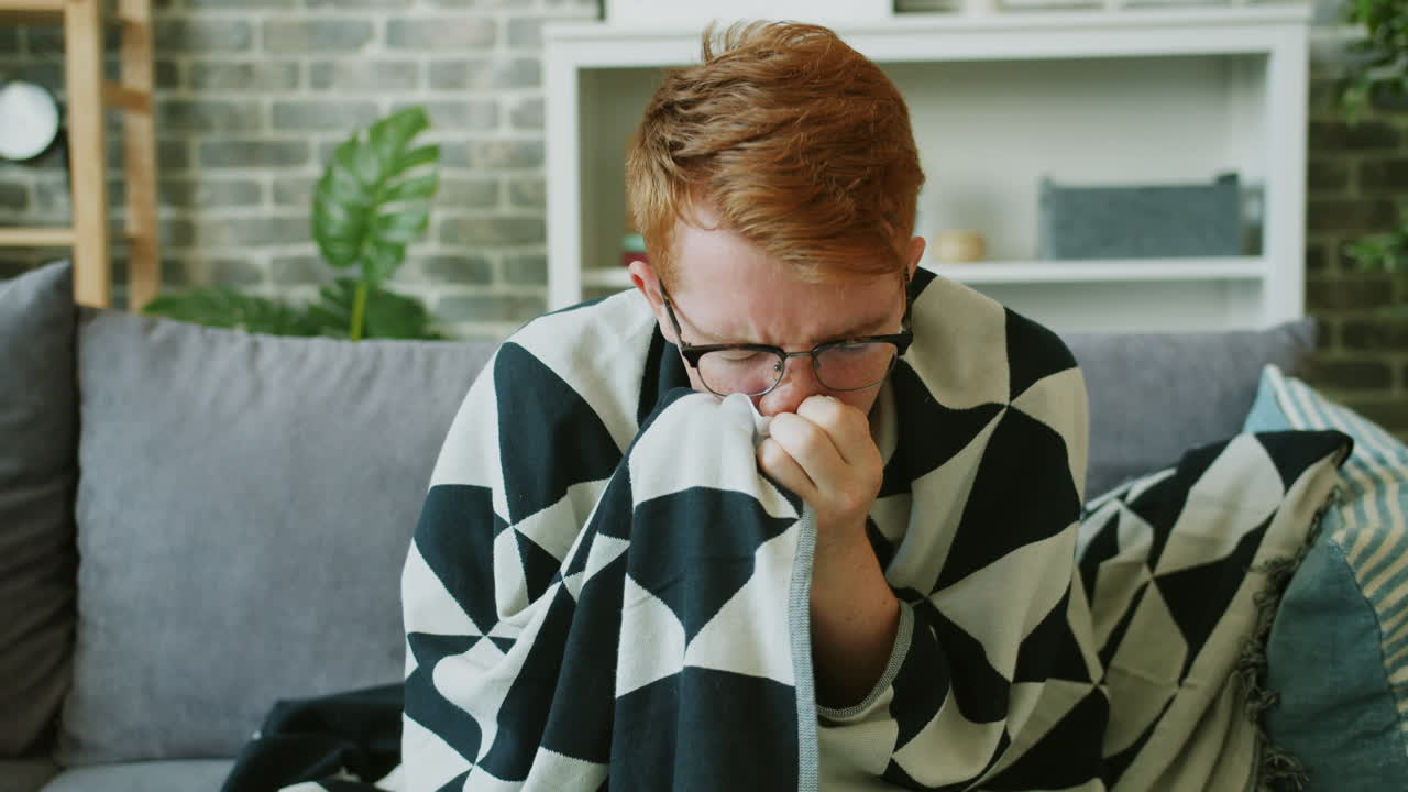 Sick Man Wrapped in a Blanket on a Couch