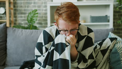 sick man wrapped in a blanket on a couch