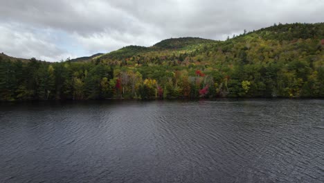 drone flying backwards over lake in new england on gloomy day