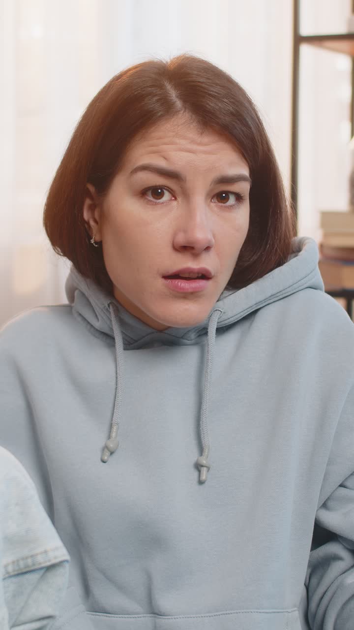 Confused caucasian woman on sofa raising eyebrows feeling embarrassed about ambiguous question