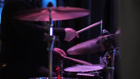 slow-motion-drummer-drumming-in-concert-indoor-side-view-artificial-lighting