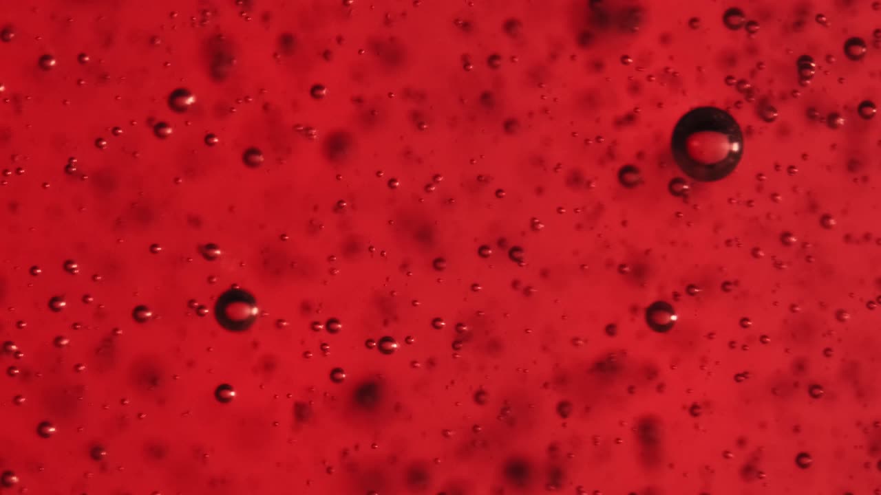 Extreme macro slow motion bubbles in red gel.  Fine bubbles rising In a glass with liquid.