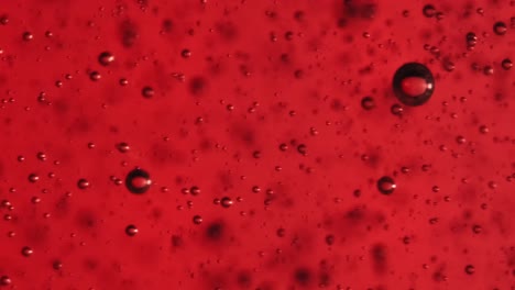 extreme macro slow motion bubbles in red gel.  fine bubbles rising in a glass with liquid.