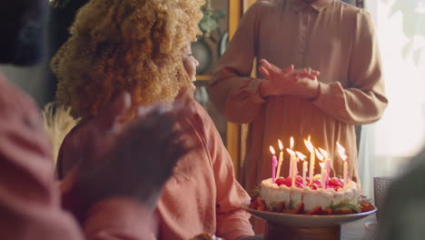 african american woman blowing candles on birthday cake
