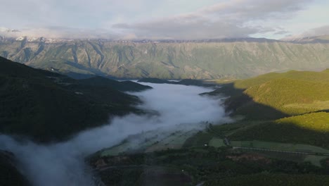 Drone-soars-toward-Albanian-hot-springs-through-fog-with-mountains-in-the-backdrop