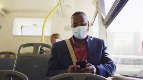 hombre afroamericano en la ciudad con cara, usando un teléfono inteligente en el autobús