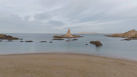 Panoramic-drone-fly-above-white-sand-coastline-rocky-sandy-islets-calm-bay-water