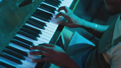 man plays musical piece on piano in club closeup. african american waiter enjoys playing instrument after shift in bar. artistic hobby and talent