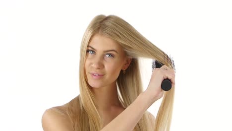 mujer cepillando su largo cabello rubio