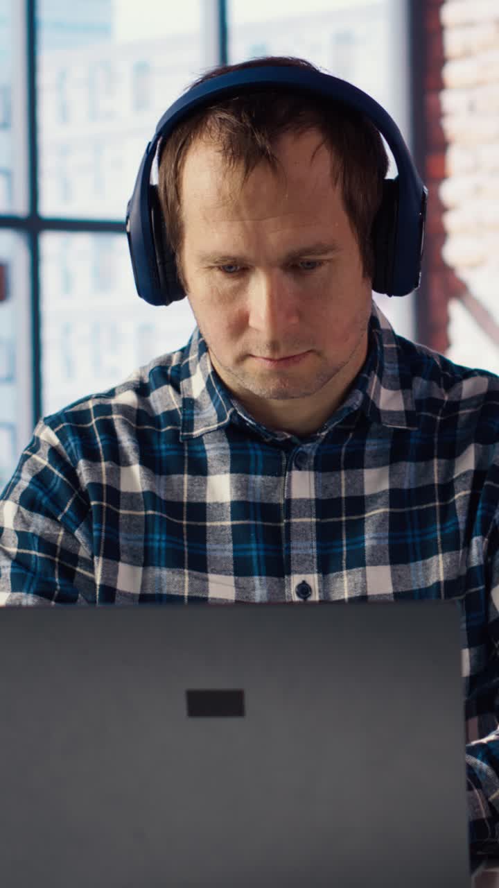 Vertical video Worker writing on paper, taking notes, listening music on laptop
