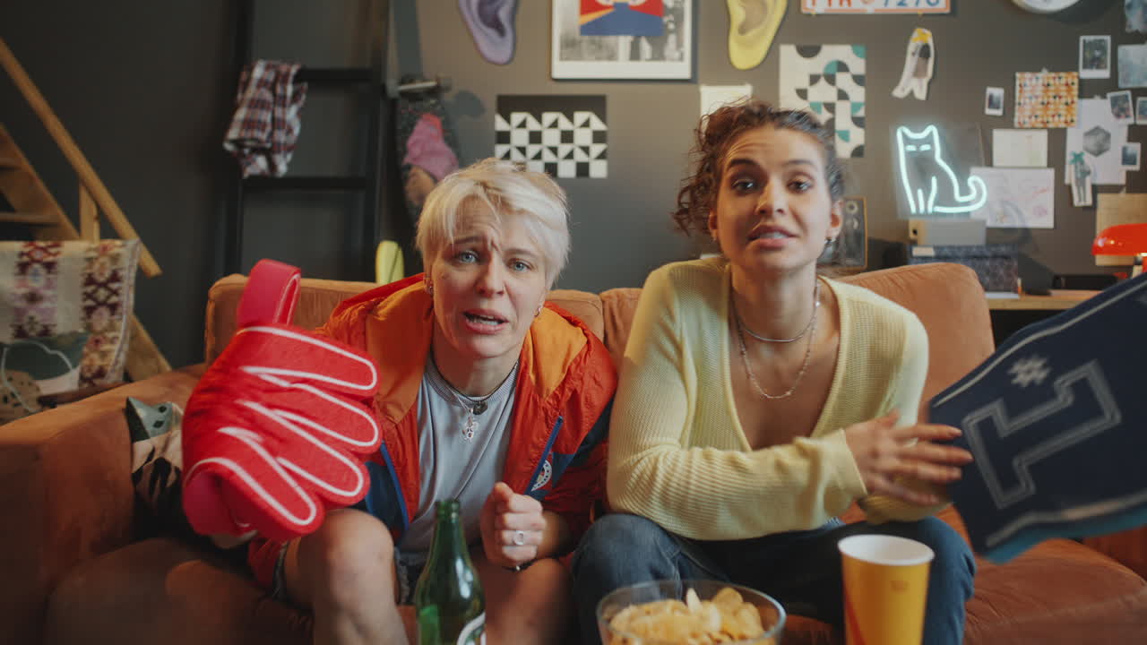 Excited Female Friends Cheering while Watching Sports on TV at Home
