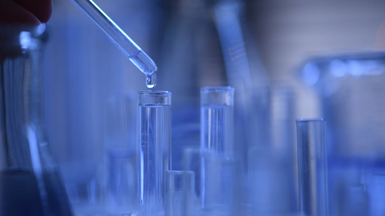 Contagocce che eroga liquido in una provetta in un laboratorio scientifico