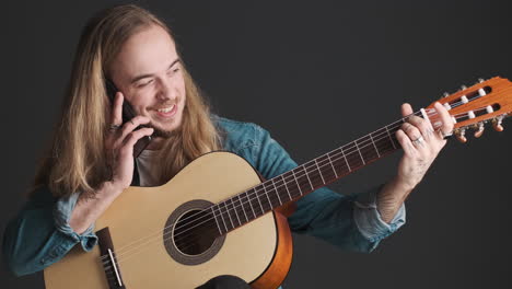 caucasian young man with guitar having a call on smartphone.