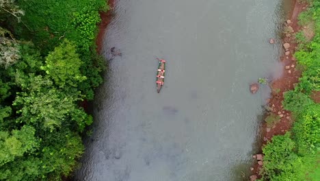 an aerial view captured by a drone showcases a serene scene of a small rowboat peacefully traversing a beautiful river in the heart of the jungle