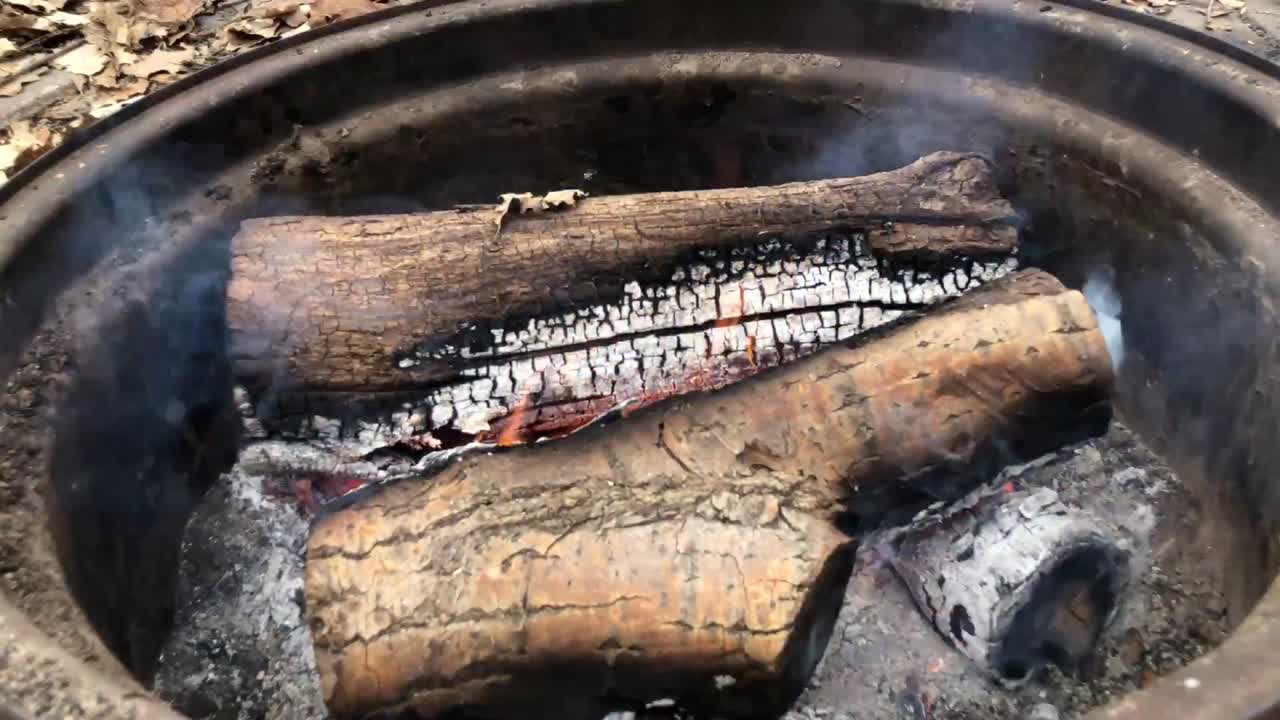 Campfire Time Lapse with small flames and lots of ash inside a metal fire ring