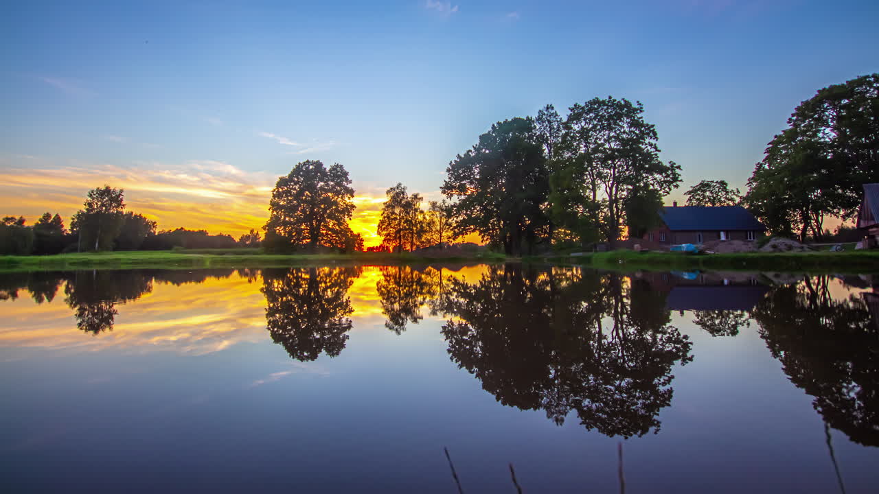 통나무집과 여전히 호수 물 뒤의 황금빛 활기찬 일몰, 융합 시간 경과