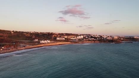 aerial view of kissonerga village in cyprus at sunset, with golden hues illuminating the buildings and beach